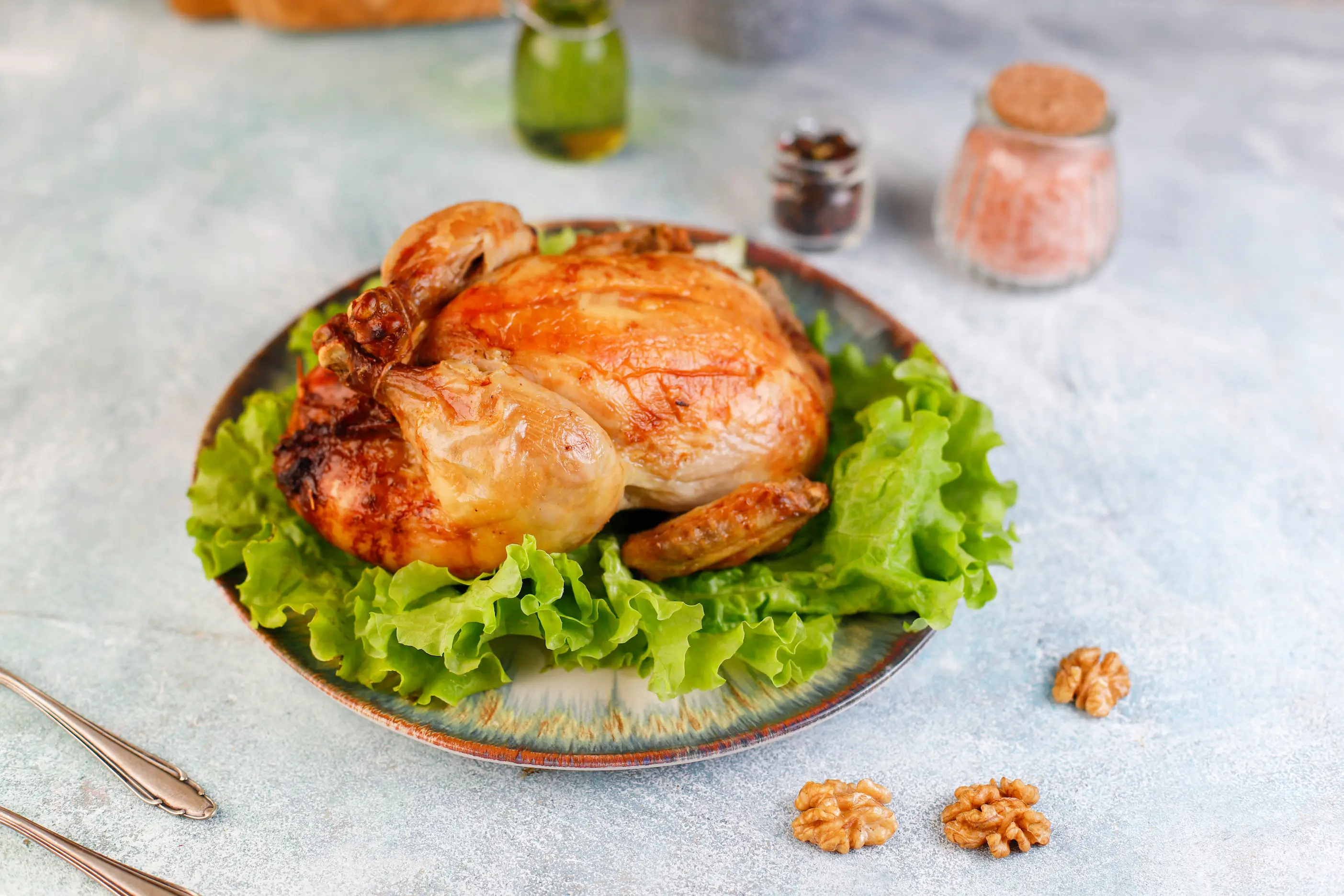 Crispy and golden-brown Azerbaijani chicken levengi served on a plate with lettuce, salt, walnut, etc.