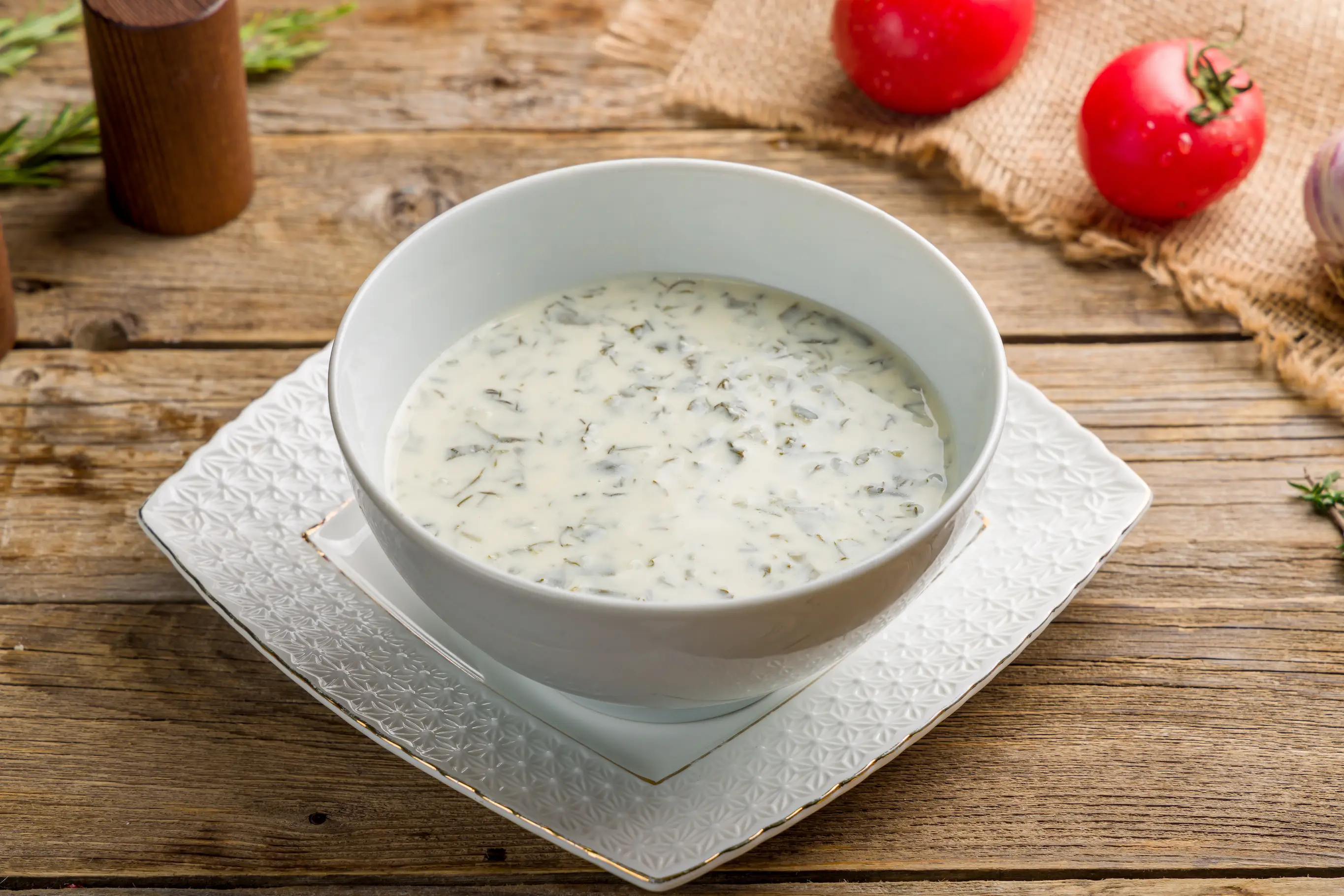Traditional Azerbaijani soup Dovga made with yoghurt, greens, etc., in a white bowl.