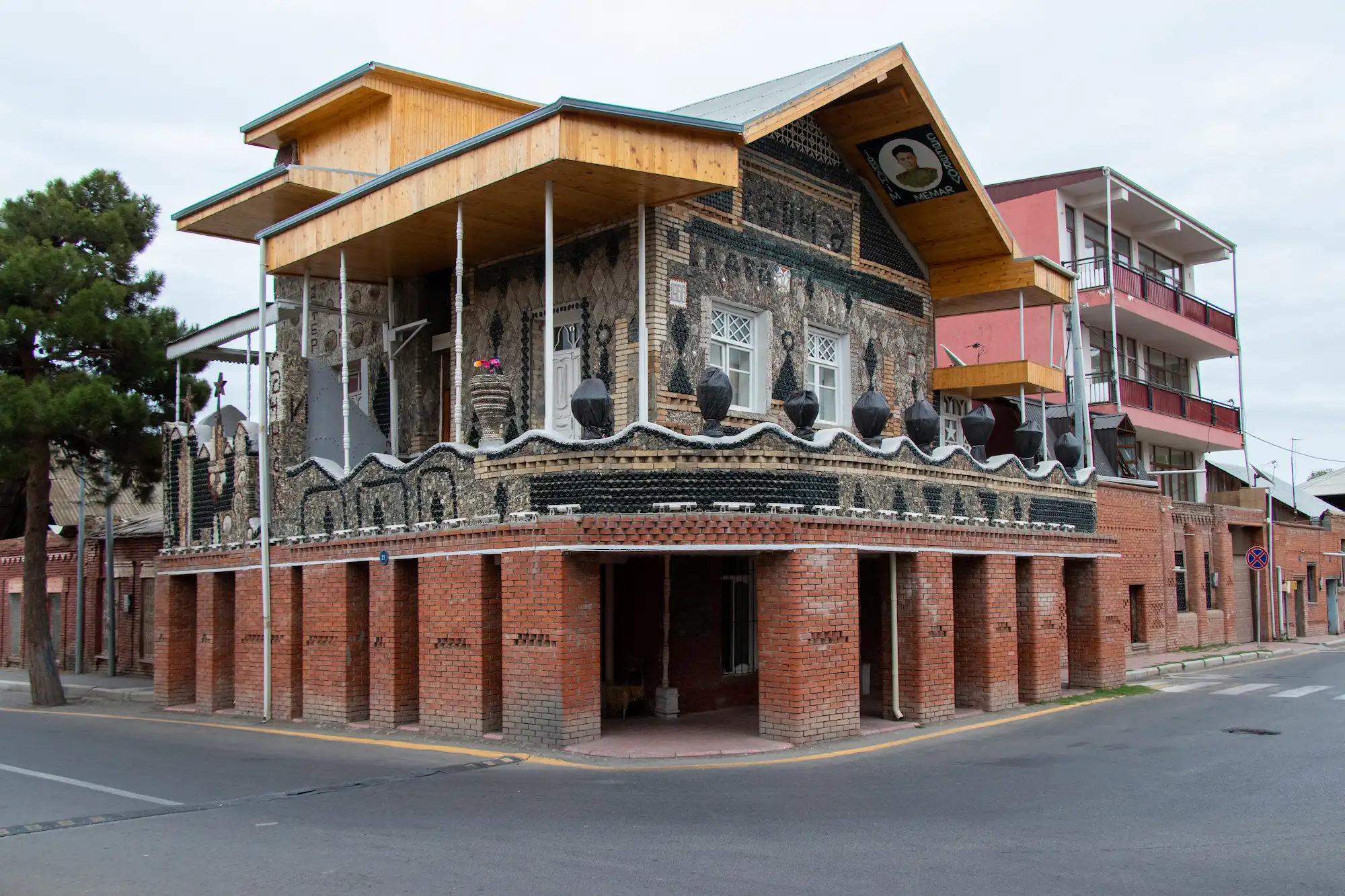 Bottle House of Ganja in Azerbaijan, a unique two-story building decorated with glass bottles and red brick walls.