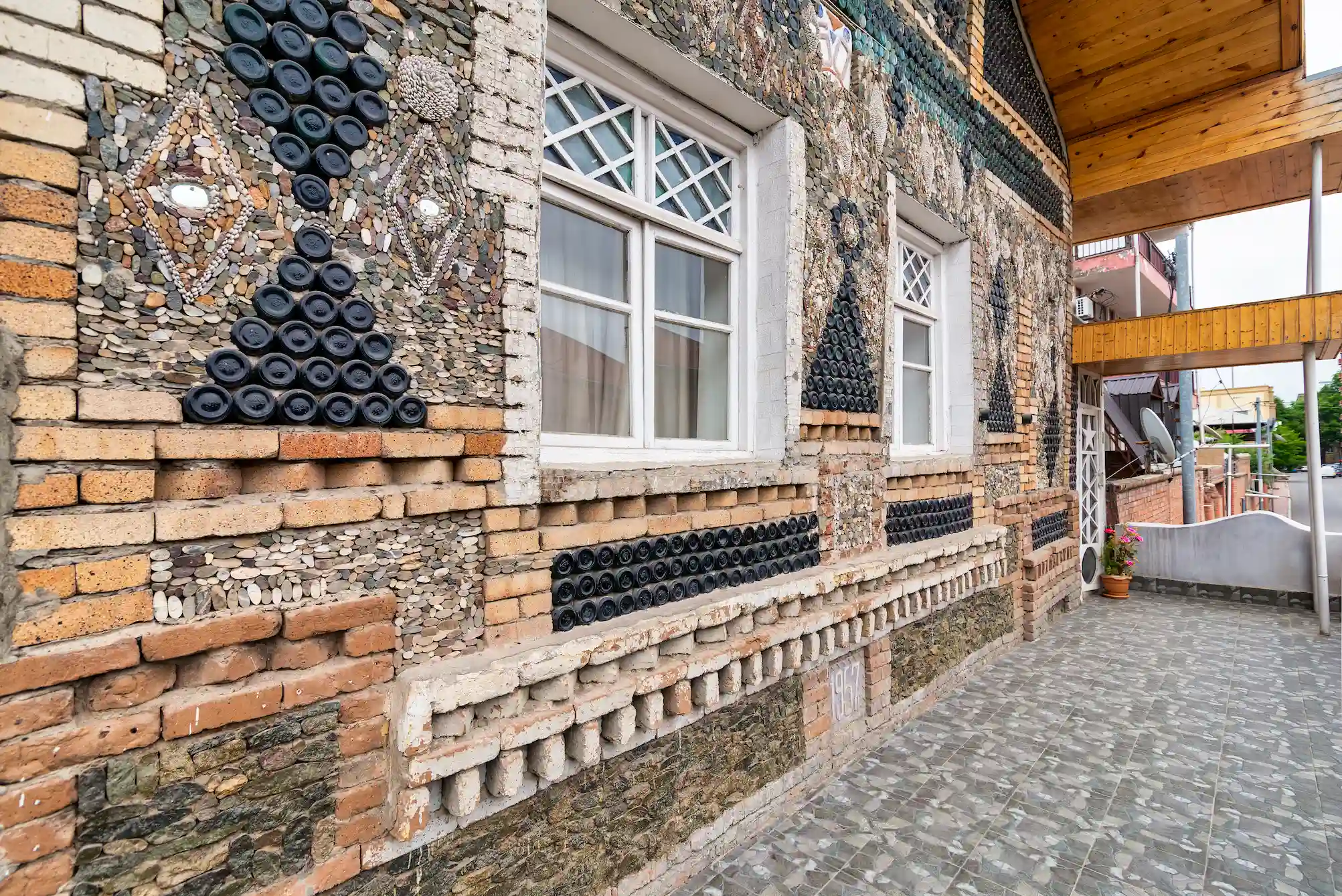 Close-up view of the Bottle House in Ganja showing its unique wall design made from glass bottles, stones, and bricks.