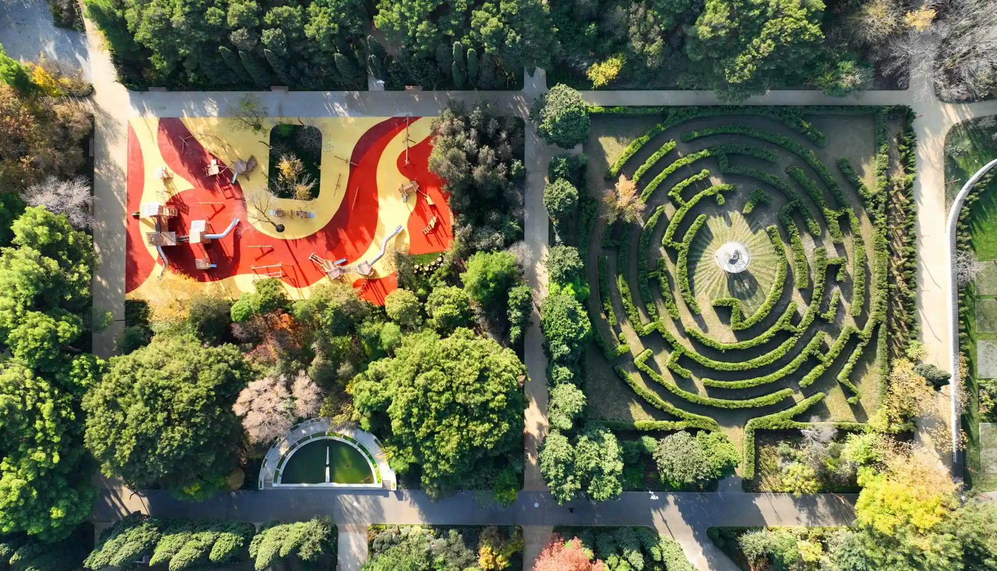 The playground for kids and labyrinth in the Central Botanical Garden of Baku, side by side, seen from a drone view at sunset.