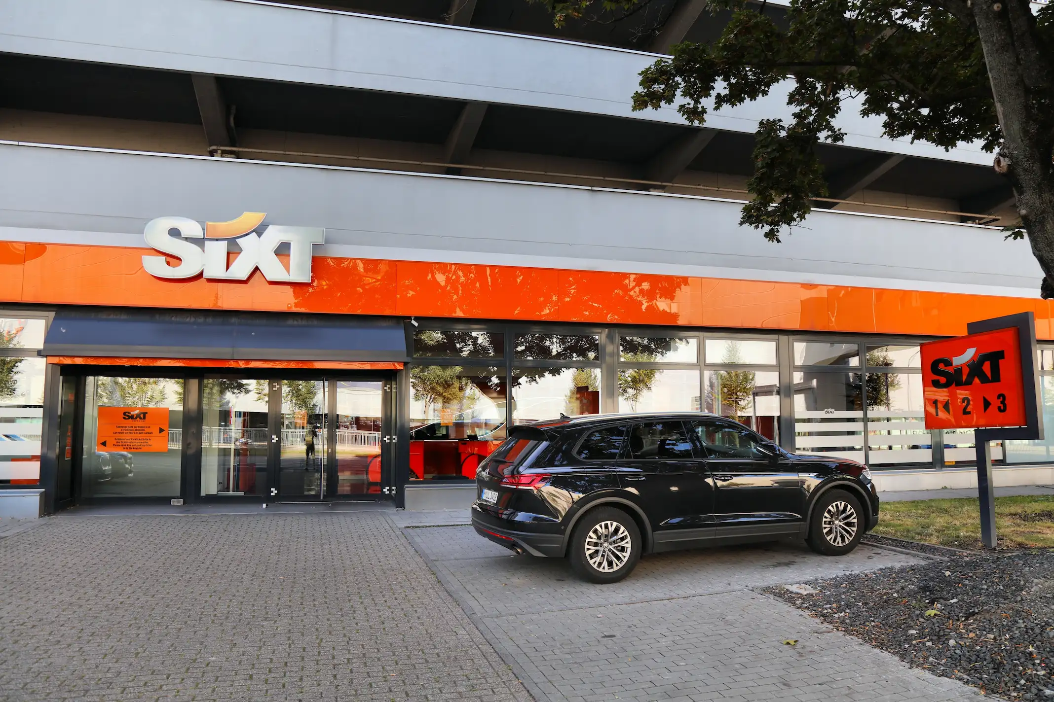 Sixt Rent a Car company with a luxury black SUV in front.