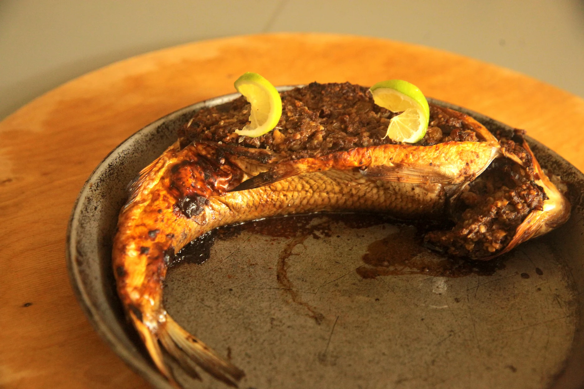 Traditional Azerbaijani fish levengi filled with walnut and other ingredients on an iron pan.