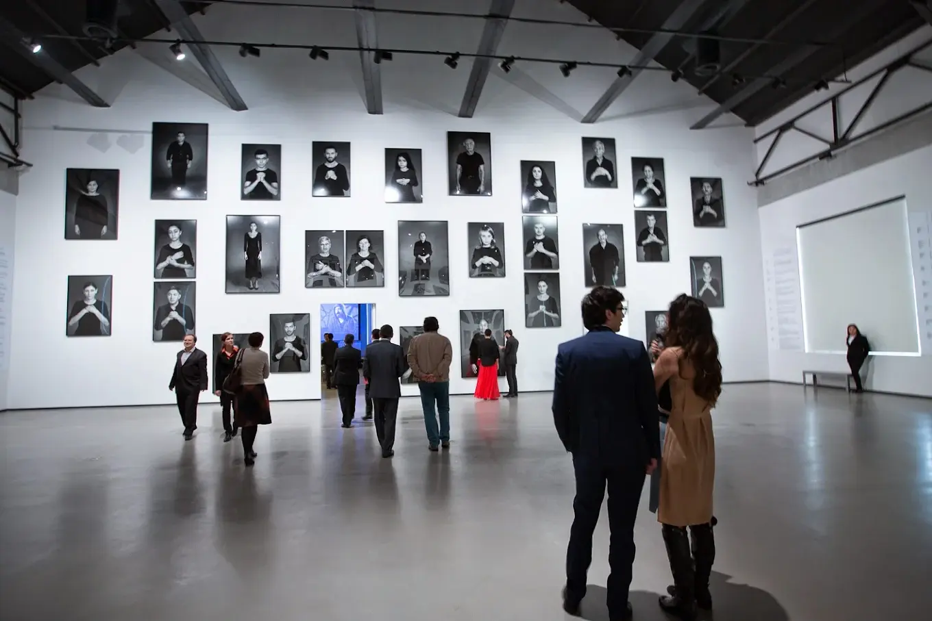 Visitors observe large black-and-white portrait photographs displayed on the walls of YARAT Contemporary Art Space during an art exhibition in Baku.