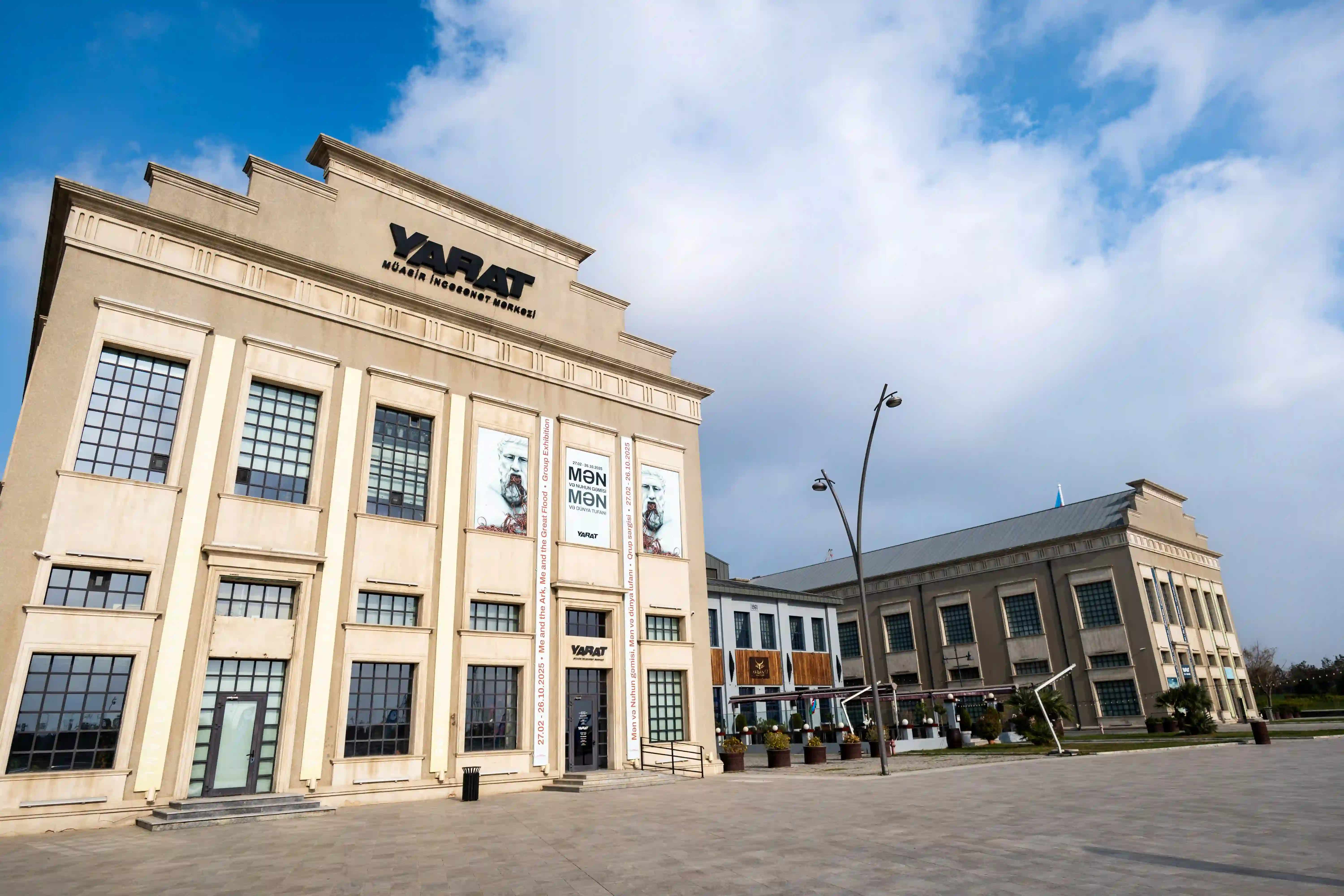 The YARAT Contemporary Art Space building in Baku stands under a bright sky, showcasing its grand architecture and banners for current exhibitions.